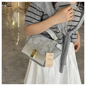 Detail of grey crossbody bag featuring crocodile texture and marble pattern flap