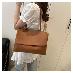Detailed side view of caramel brown leather tote bag worn as a shoulder bag