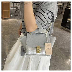 Detail of grey crocodile pattern and matte suede texture on the trapezoid handbag