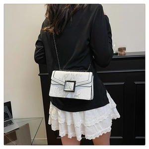 Close-up of a white and grey snakeskin print crossbody bag with metallic chain strap