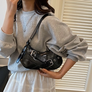 Chic black patent leather baguette bag with silver buckles and punk rivets on a model