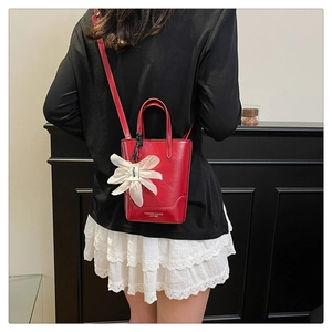 Detailed view of red leather bucket bag with white organza flower charm and strap