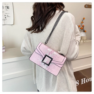 Detail of pink snake pattern crossbody bag with metal chain strap and black square buckle