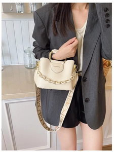 Detail of cream leather bucket bag with metal handle and woven monogram shoulder strap