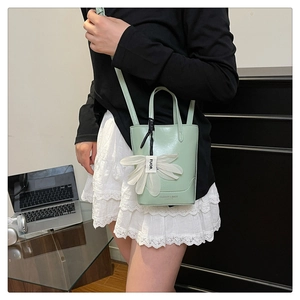 Detail of mint green mini bucket bag with white floral charm and logo print
