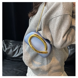 Detail of light blue mini evening bag with large gold ring handle and chain strap