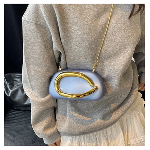Detail of light blue crossbody bag with unique gold ring handle and delicate chain strap