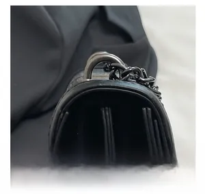 Detailed macro view of black chain strap and gunmetal hardware on textured crossbody bag