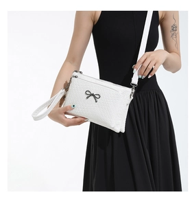 Detail of white woven texture bag with black bow pendant and detachable shoulder strap