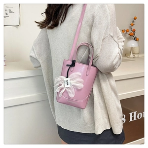 Close-up of pink mini bucket bag with fashion lettering and floral silk accessory