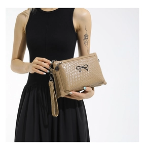 Detail of khaki woven texture bag with black metal bow and multi-layer zipper design