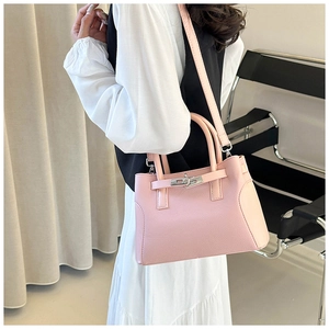Sac à main rose en cuir grainé avec fermoir rotatif métallique porté à l'épaule