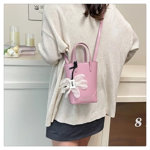 Detail of pink leather mini tote bag with a white chiffon flower charm on a crossbody strap
