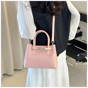 Sac à main en cuir rose avec fermoir en métal porté en bandoulière par un mannequin