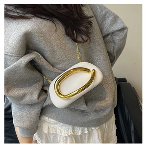 Detail of white mini evening bag with a large gold metal buckle and thin gold chain strap