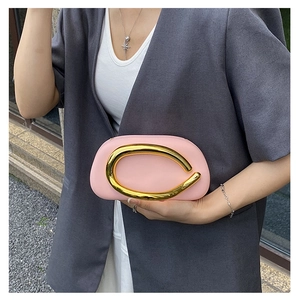 Detail of pink evening clutch bag with curved gold metal handle and luxury finish