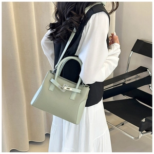 Détail d'un sac à main vert clair en cuir grainé avec fermoir rotatif et bandoulière amovible
