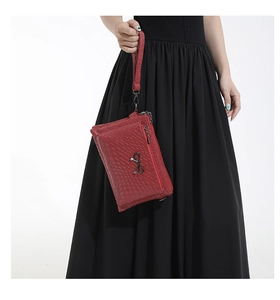 Detail of red woven texture handbag featuring black metal bow and multi-layer zippers