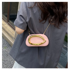 Detail of pink mini clutch with golden handle and chain strap on a model shoulder