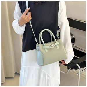 Détail d'un sac à main en cuir vert pistache avec boucle métallique et décor minimaliste