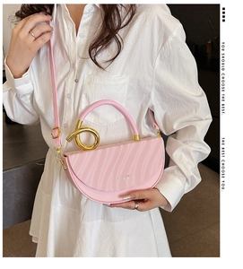 Detail of pink saddle bag with golden spiral handle and textured leather finish