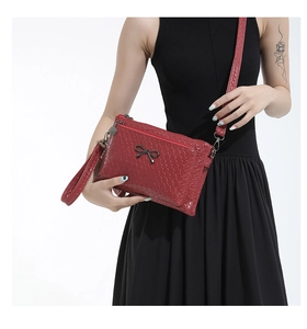 Close-up of red woven texture handbag featuring a decorative black metal bow buckle
