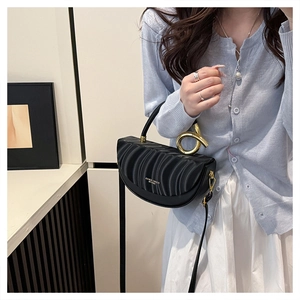 Detail of black pleated saddle bag featuring a unique gold metal knot ring handle