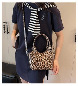 Detail shot of leopard print handbag with glossy finish and silver hardware on model