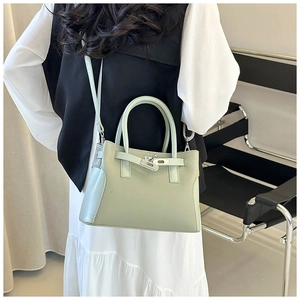 Détail d'un sac à main vert menthe avec fermoir métallique porté par un mannequin