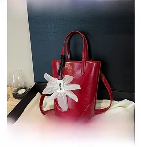 Detail of red leather mini tote bag with white flower charm and thin shoulder strap