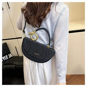 Detailed shot of black saddle bag with wavy pleated leather and golden metal handle