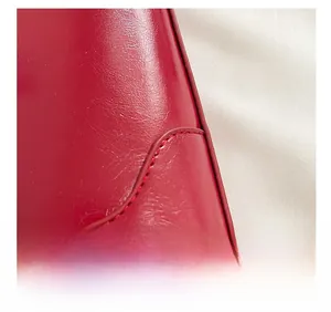 Close-up of red leather tote bag showing fine grain texture and premium stitching detail