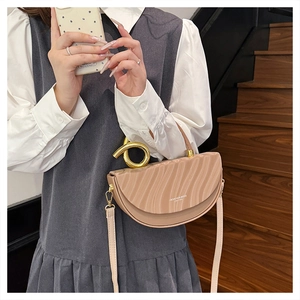 Detail of beige half-moon saddle bag featuring unique pleated texture and gold knot handle