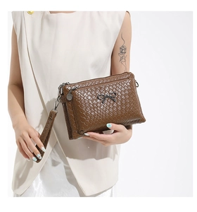 Detail of woven texture dark brown handbag with metal bow and multi-layer zippers