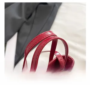 Macro shot of red tote bag handle with fine stitching and smooth leather texture