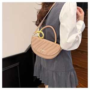 Detail of apricot saddle bag with wavy texture and gold ring handle worn by model