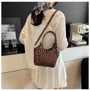 Chic leopard print bucket bag with round knotted handles styled in a modern city cafe
