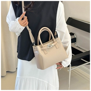 Détail du sac à main beige en cuir grainé avec fermoir rotatif argenté et poignée