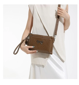 Detail of brown woven PU leather bag with black metal bow and detachable straps