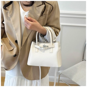 Détail d'un sac à main blanc en cuir grainé avec fermoir rotatif argenté et bandoulière