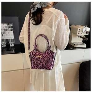 Detail of purple leopard print handbag with knot handle and gold hardware in a cafe
