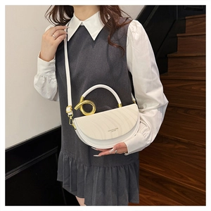 Detail of white half-moon saddle bag with golden circular handle on an elegant model