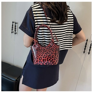 Detail view of red leopard print handbag with glossy finish and dual carrying straps