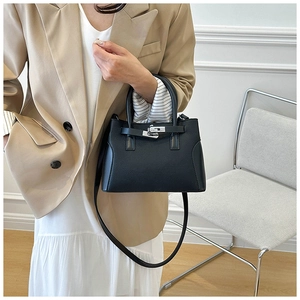 Détail de la texture cuir noir grainé et boucle métallique sur le sac à main