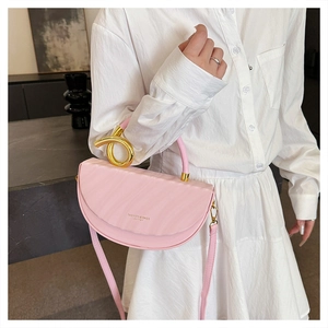 Detailed macro view of pink saddle bag featuring golden knot metal ring and logo