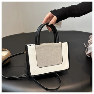 Detail of color-block tote bag with white leather, beige canvas and black strap