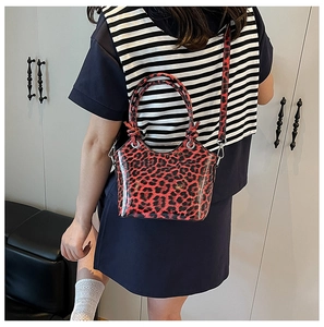 Detail of red leopard print bucket bag with glossy finish and detachable crossbody strap