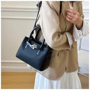 Vue détaillée du sac à main en cuir noir avec fermoir rotatif argenté sur un mannequin