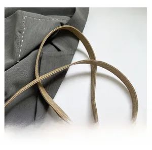 Detail of light khaki woven leather texture and slim shoulder strap on fashion crossbody bag