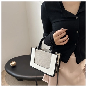 Detail of a minimalist two-tone crossbody bag featuring premium leather and canvas textures